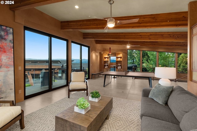 interior space featuring beamed ceiling, ceiling fan, and a healthy amount of sunlight