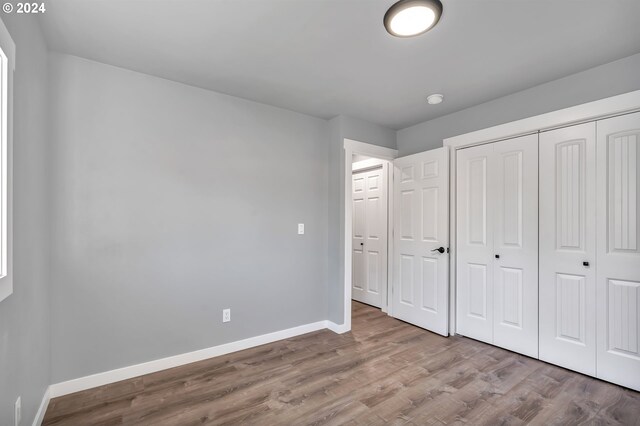 unfurnished bedroom featuring a closet and hardwood / wood-style flooring