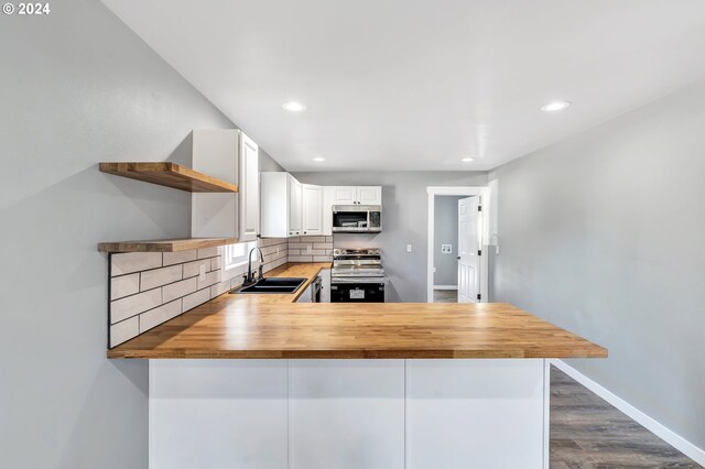 kitchen with white cabinets, stainless steel appliances, tasteful backsplash, and butcher block countertops