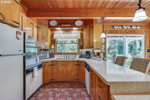 kitchen featuring sink, beam ceiling, white appliances, and a healthy amount of sunlight