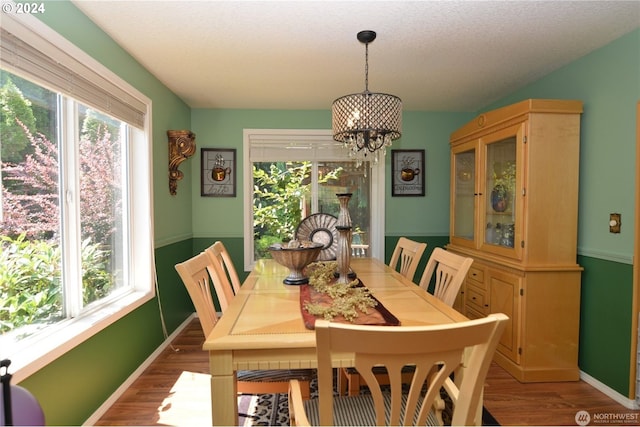 dining space with hardwood / wood-style flooring, an inviting chandelier, and a textured ceiling