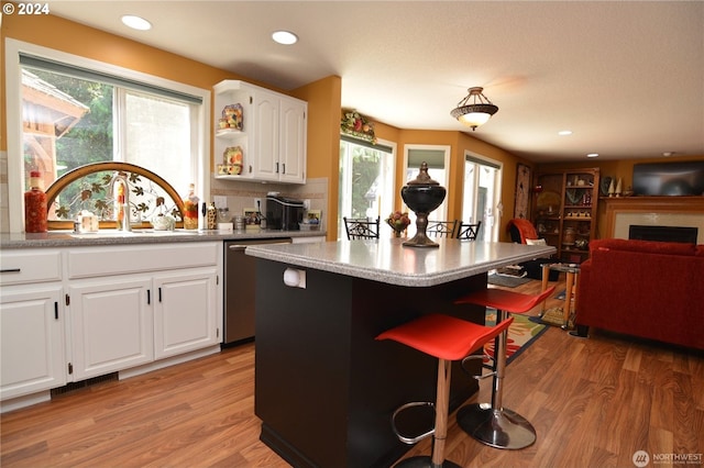 kitchen featuring dishwasher, a breakfast bar, white cabinets, and light hardwood / wood-style flooring