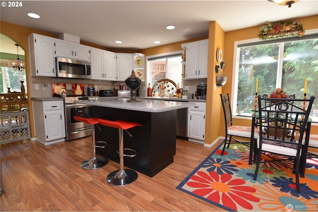 kitchen featuring white cabinetry, appliances with stainless steel finishes, a kitchen island, and backsplash