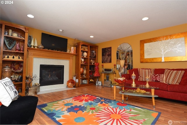 living room with wood-type flooring and a tile fireplace