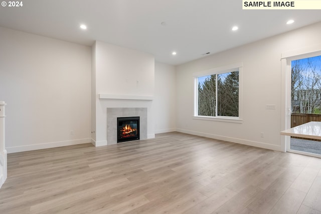 unfurnished living room featuring light wood-type flooring and a tiled fireplace