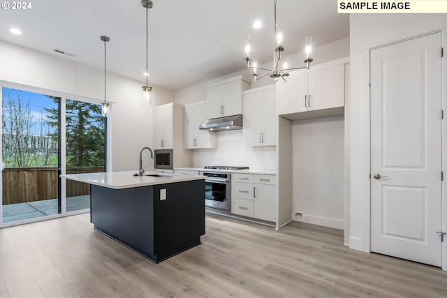 kitchen with appliances with stainless steel finishes, hanging light fixtures, sink, and white cabinetry