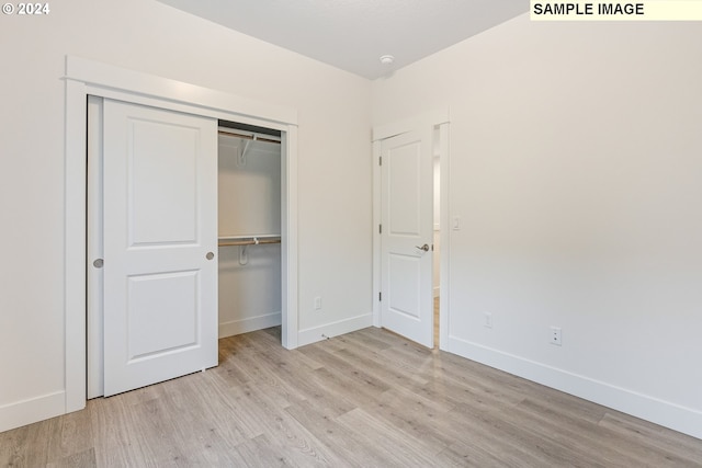 unfurnished bedroom featuring light wood-type flooring and a closet