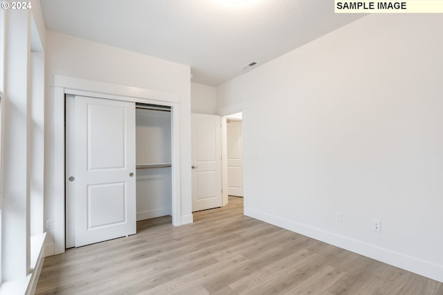 unfurnished bedroom featuring light wood-type flooring and a closet