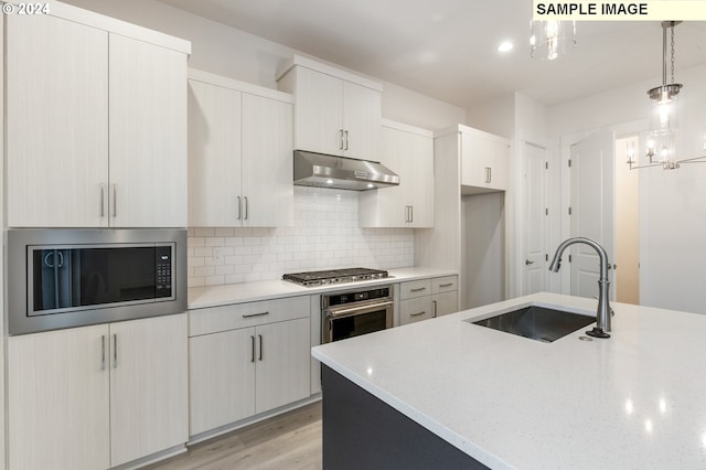 kitchen with decorative backsplash, stainless steel appliances, sink, light hardwood / wood-style floors, and hanging light fixtures