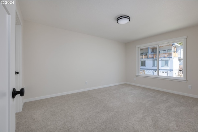 empty room featuring light colored carpet and baseboards