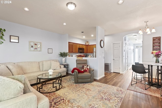 living area featuring recessed lighting, arched walkways, an inviting chandelier, and wood finished floors