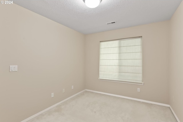 empty room with visible vents, baseboards, light colored carpet, and a textured ceiling