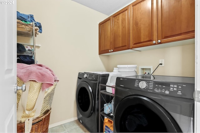 laundry area featuring washer and dryer, light tile patterned floors, baseboards, and cabinet space