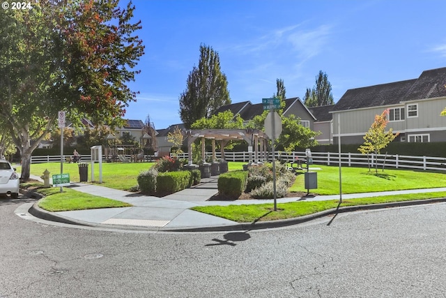 view of property's community with a lawn and a pergola