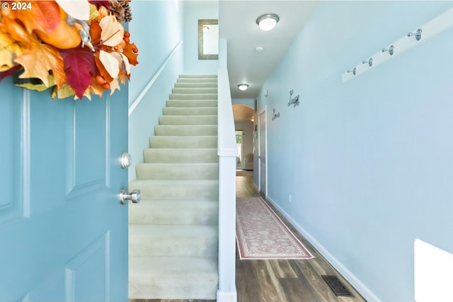 staircase featuring visible vents, baseboards, arched walkways, and wood finished floors
