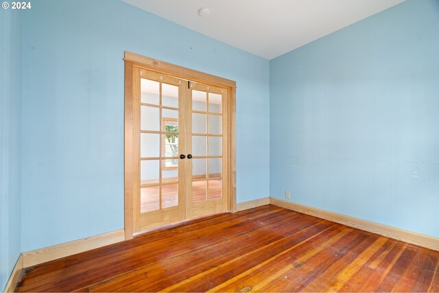 empty room with hardwood / wood-style flooring and french doors