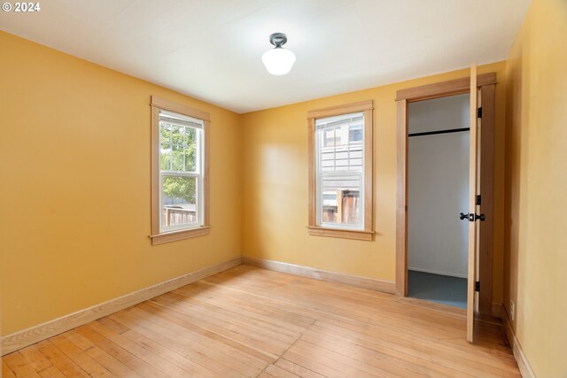 unfurnished bedroom featuring light wood-type flooring and multiple windows