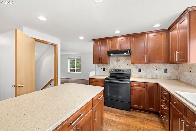 kitchen featuring light hardwood / wood-style floors, light stone countertops, black range with electric stovetop, and backsplash