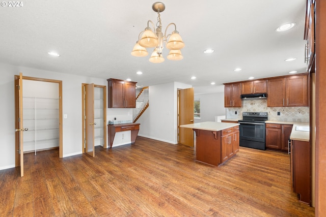 kitchen featuring a breakfast bar area, dark wood-type flooring, black range with electric cooktop, a center island, and decorative light fixtures