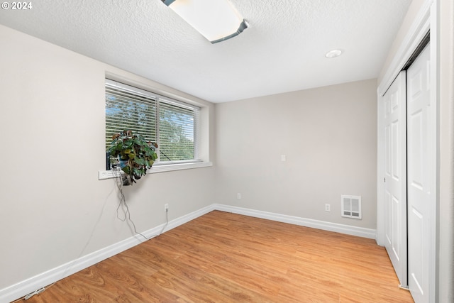 unfurnished bedroom featuring light hardwood / wood-style flooring, a textured ceiling, and a closet