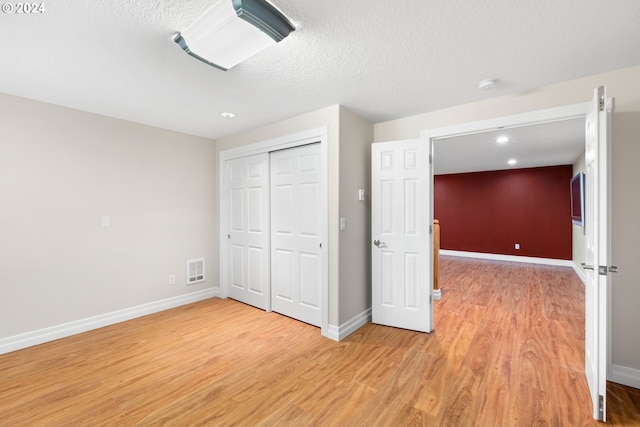 unfurnished bedroom with a closet, a textured ceiling, and hardwood / wood-style floors