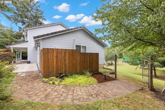 view of side of home featuring a patio area and a lawn