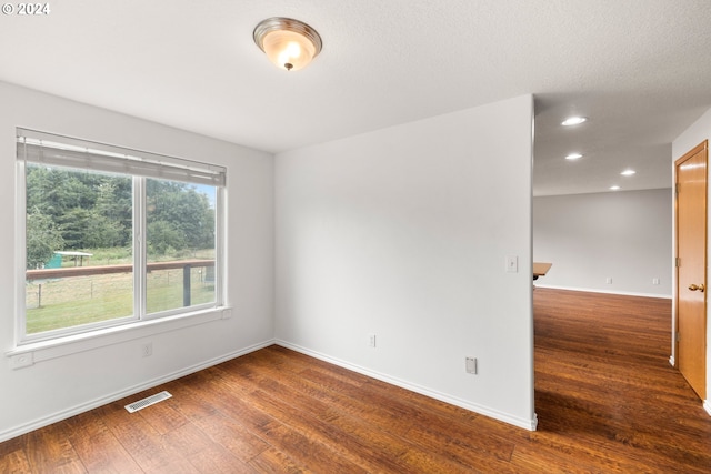 empty room with a textured ceiling and dark hardwood / wood-style floors