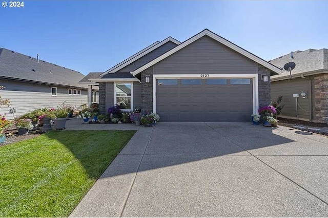view of front of property featuring an attached garage, stone siding, driveway, and a front yard