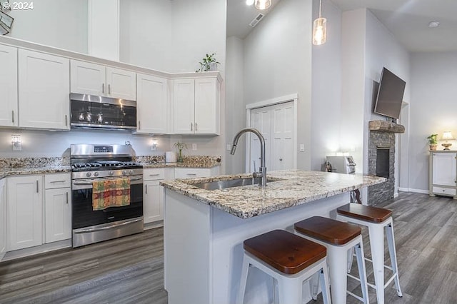 kitchen with appliances with stainless steel finishes, white cabinetry, light stone counters, and a fireplace