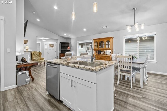 kitchen with sink, vaulted ceiling, decorative light fixtures, white cabinets, and light stone counters