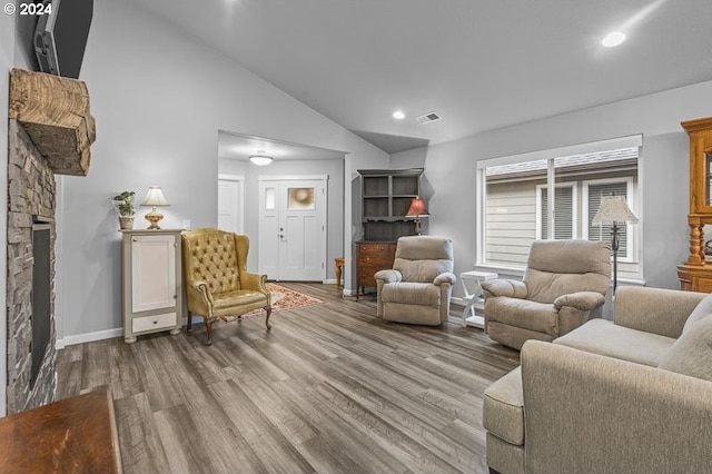 living room with light hardwood / wood-style flooring, lofted ceiling, and a fireplace