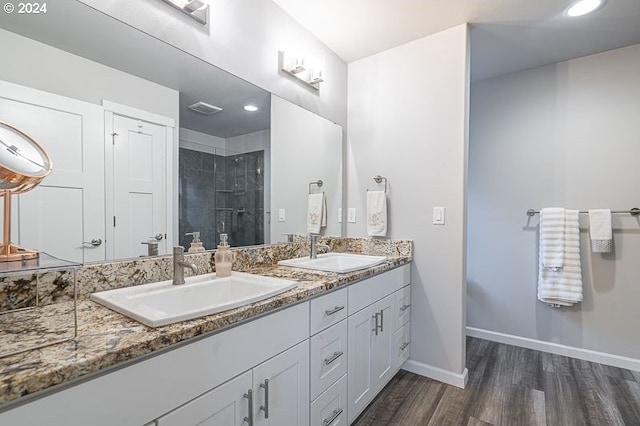bathroom featuring baseboards, wood finished floors, a sink, and a stall shower