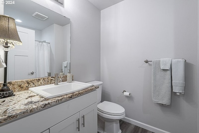 full bath with wood finished floors, vanity, baseboards, toilet, and visible vents