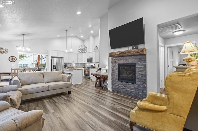 living room with a textured ceiling, high vaulted ceiling, wood-type flooring, and a fireplace