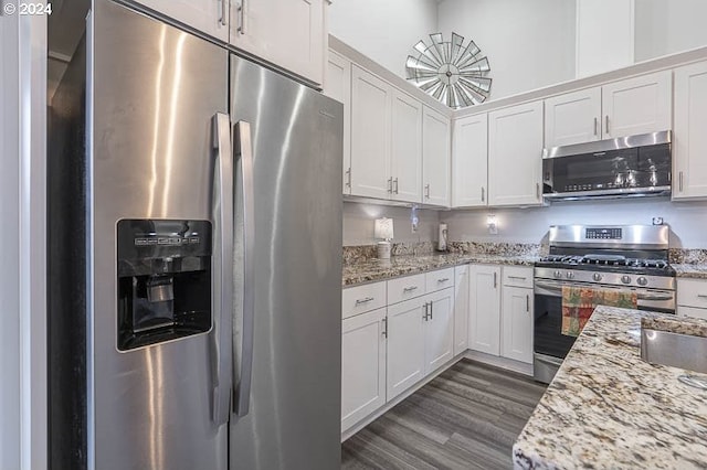 kitchen featuring white cabinetry, light stone counters, appliances with stainless steel finishes, and dark hardwood / wood-style floors