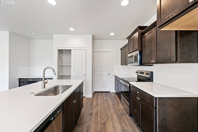 kitchen with dark hardwood / wood-style flooring, stainless steel appliances, tasteful backsplash, sink, and dark brown cabinets