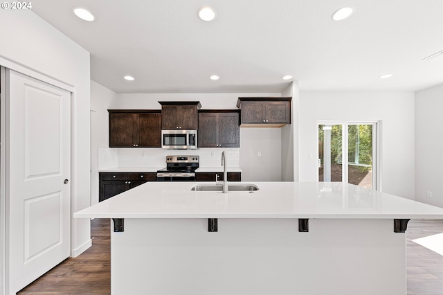 kitchen featuring a kitchen bar, sink, stainless steel appliances, and a kitchen island with sink