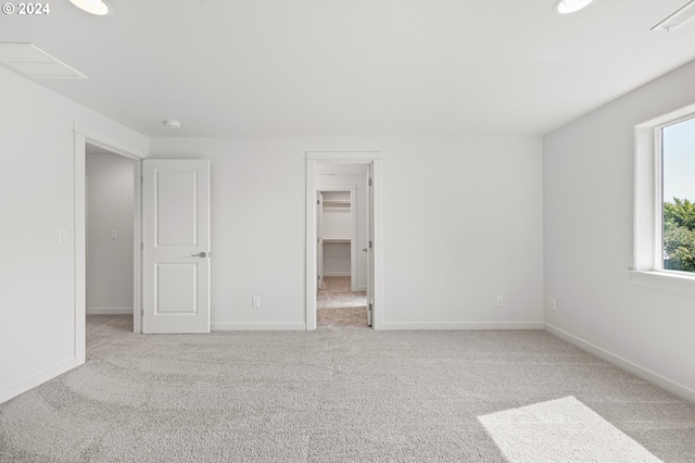 unfurnished bedroom with light carpet, a closet, and a walk in closet