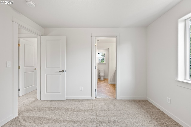 unfurnished bedroom with light colored carpet and ensuite bathroom