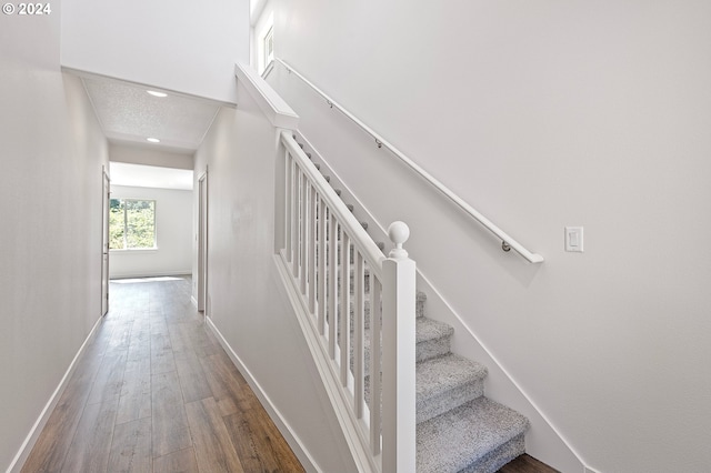 staircase with hardwood / wood-style flooring and a textured ceiling