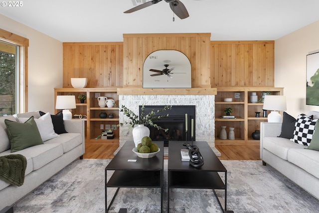 living room featuring wood-type flooring, a stone fireplace, and wood walls