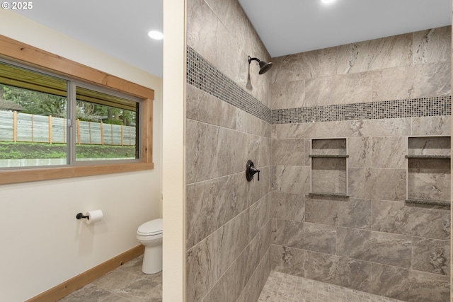 bathroom featuring a tile shower and toilet