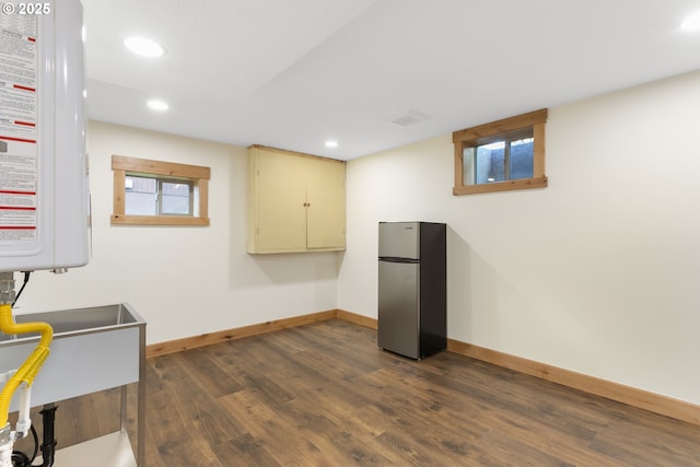 basement featuring stainless steel fridge and dark wood-type flooring