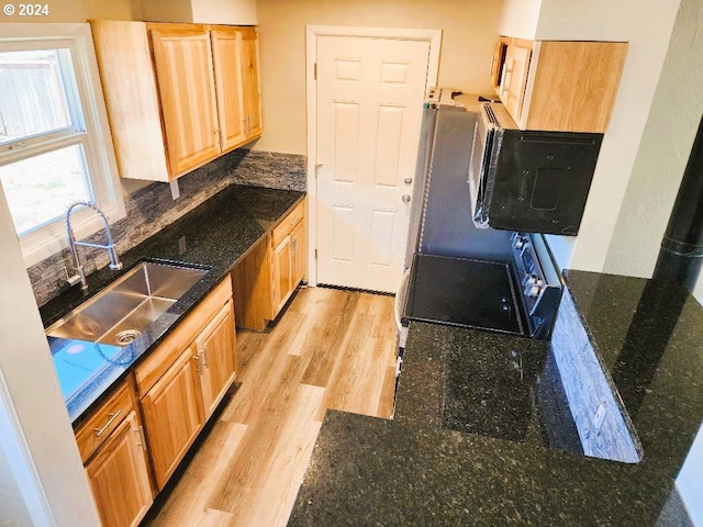 kitchen with sink, light hardwood / wood-style floors, dark stone countertops, and light brown cabinetry