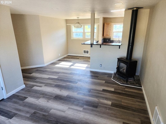 unfurnished living room with dark wood-type flooring and a wood stove