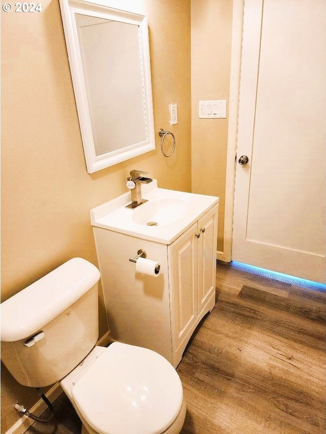 bathroom featuring toilet, vanity, and hardwood / wood-style floors