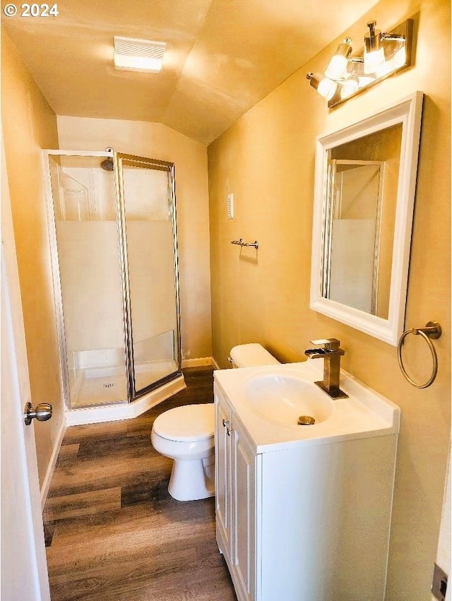 bathroom featuring vaulted ceiling, toilet, wood-type flooring, vanity, and a shower with shower door