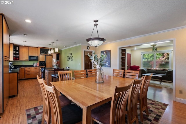 dining space featuring light wood-type flooring, crown molding, and sink