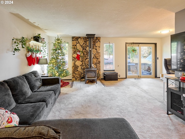 living room featuring carpet floors, a textured ceiling, and a wood stove