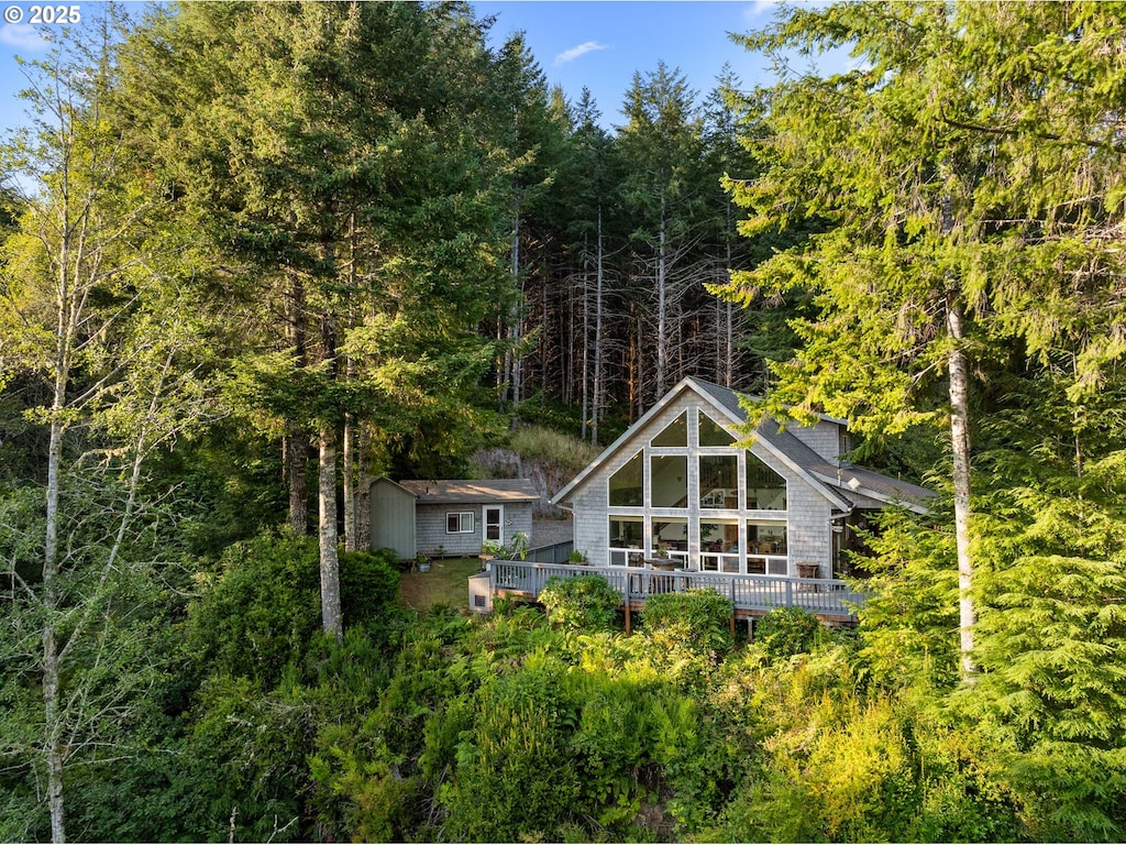 back of house featuring a wooden deck and a storage unit